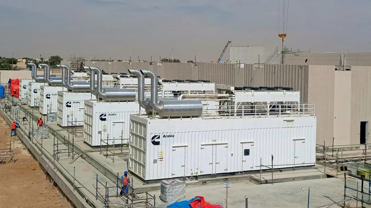Row of white industrial generators installed at a facility under construction.