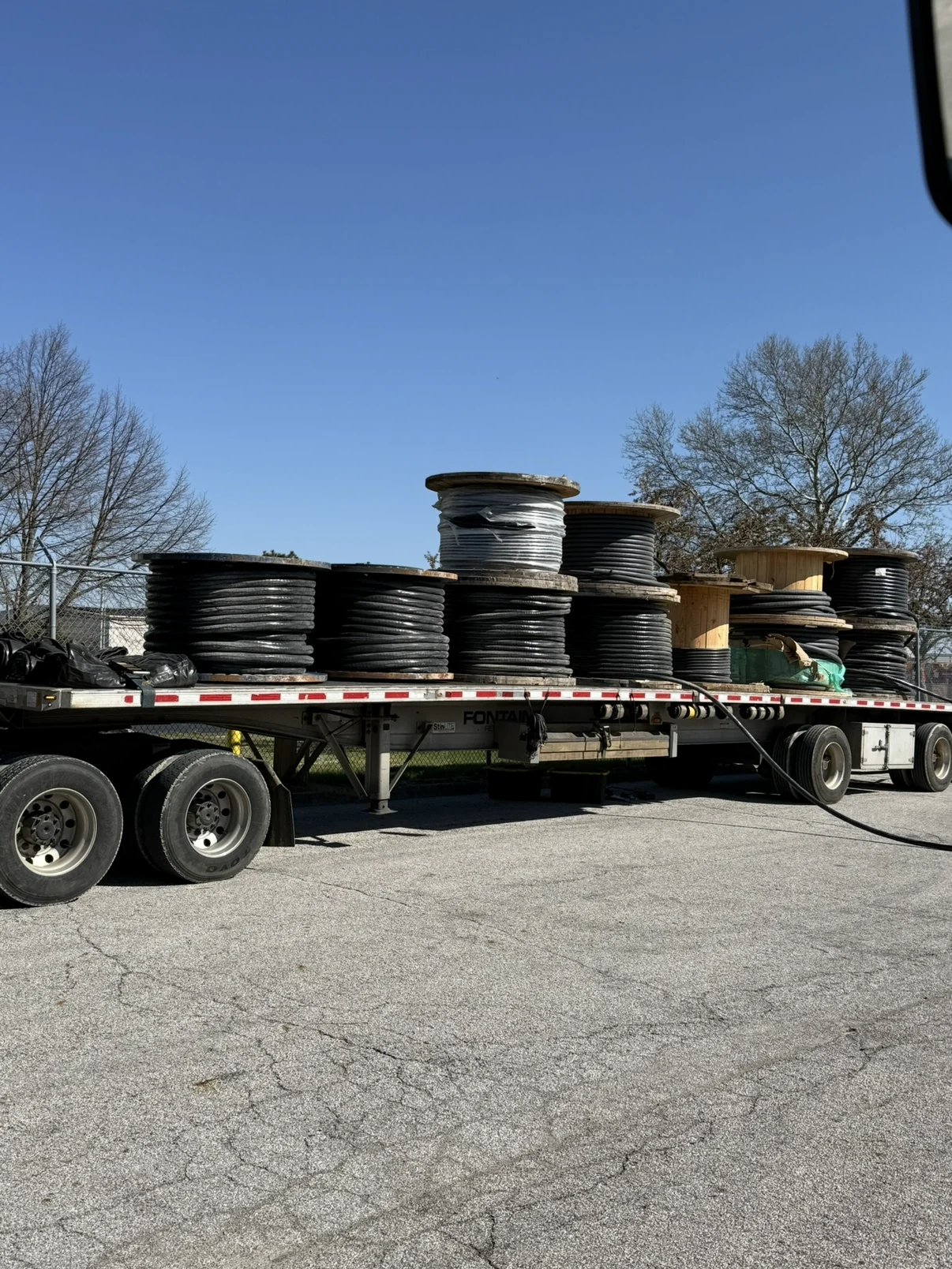 Large electrical cable spools loaded on a flatbed trailer.