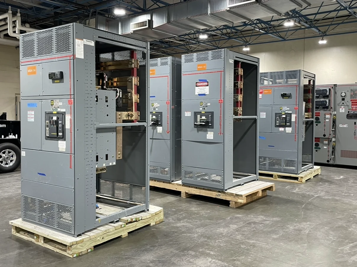 Gray switchgear sections on pallets in an industrial warehouse.