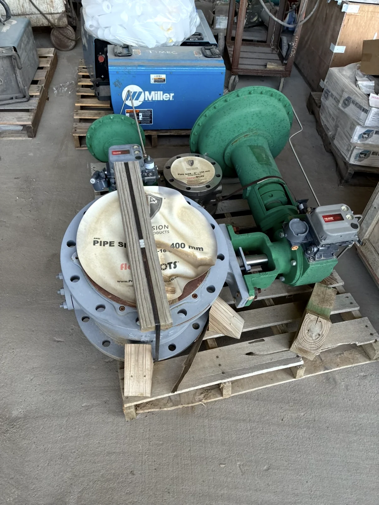 Large industrial valve with green actuator secured to a pallet.
