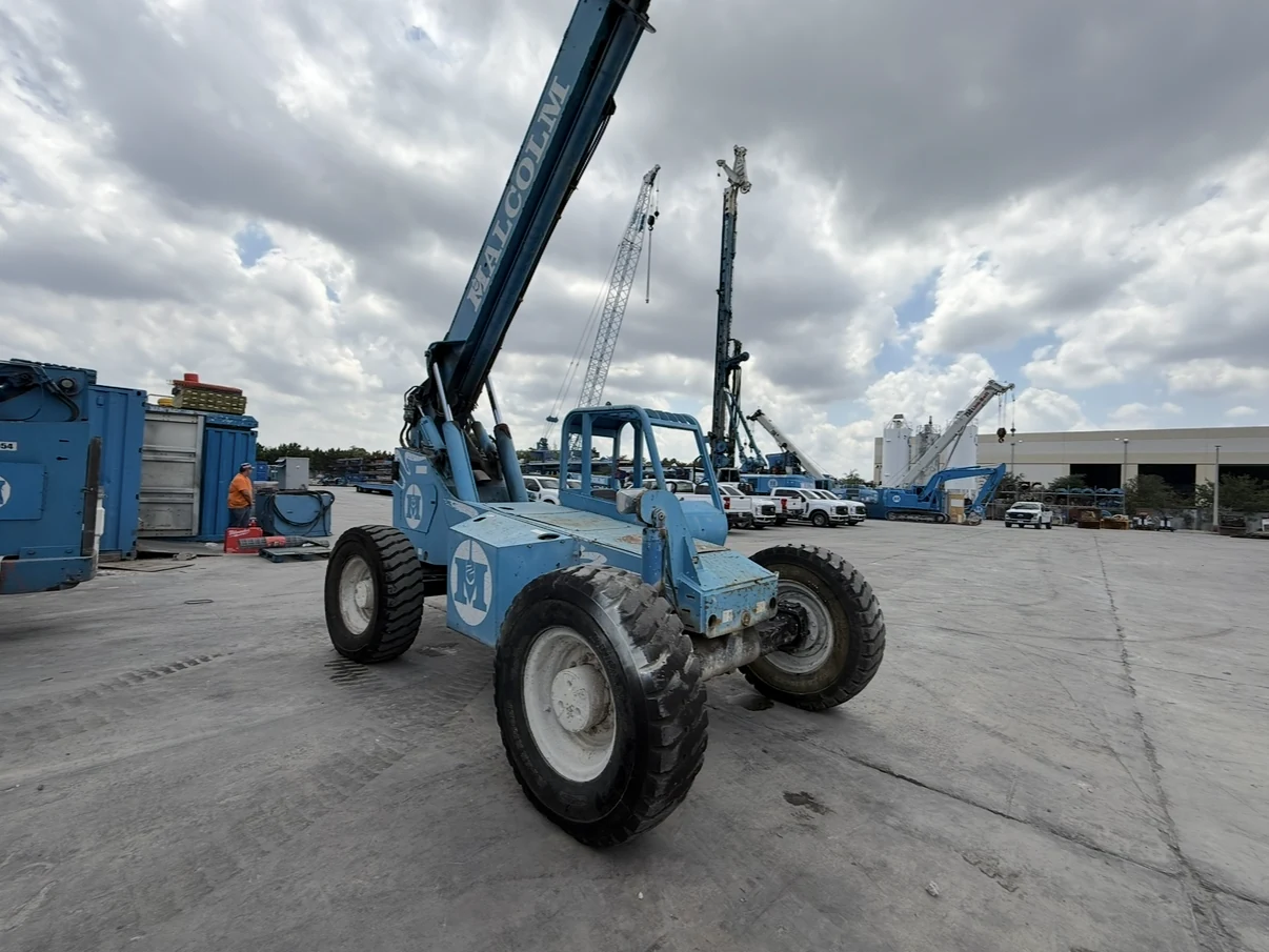 Blue telehandler parked on a concrete equipment lot.