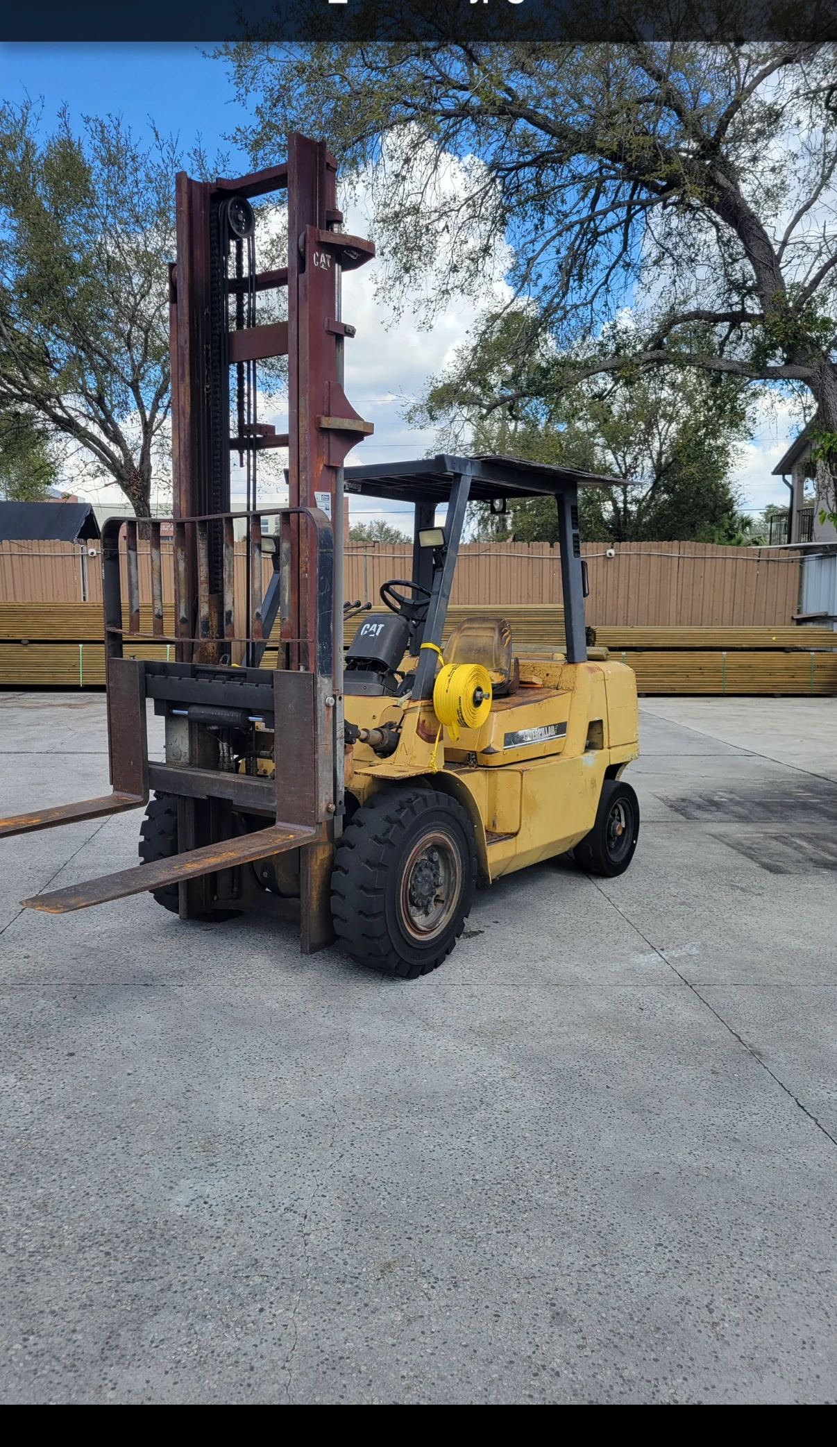 Yellow Caterpillar forklift parked outdoors on concrete.