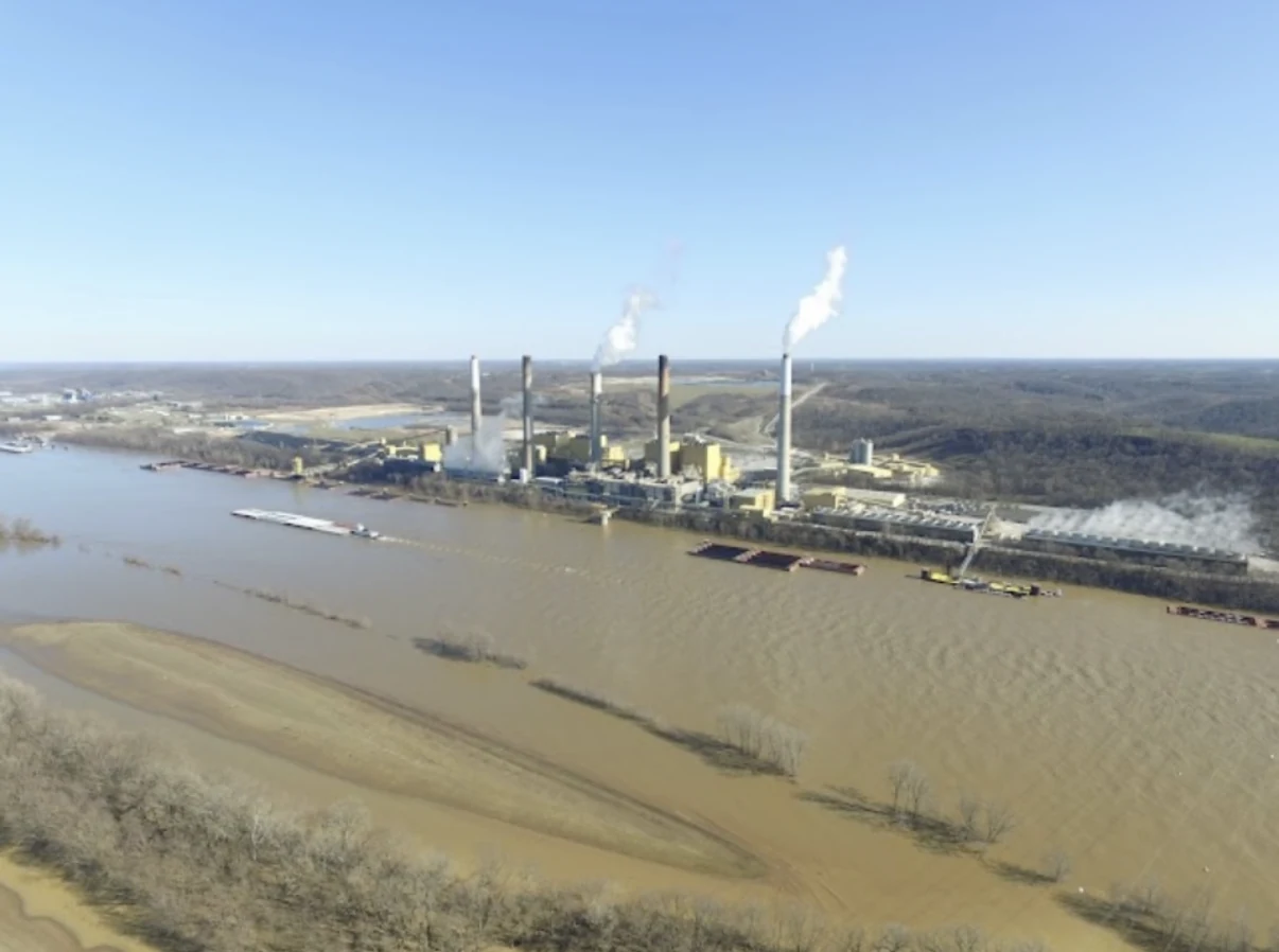 Industrial power plant beside a river with multiple smokestacks.