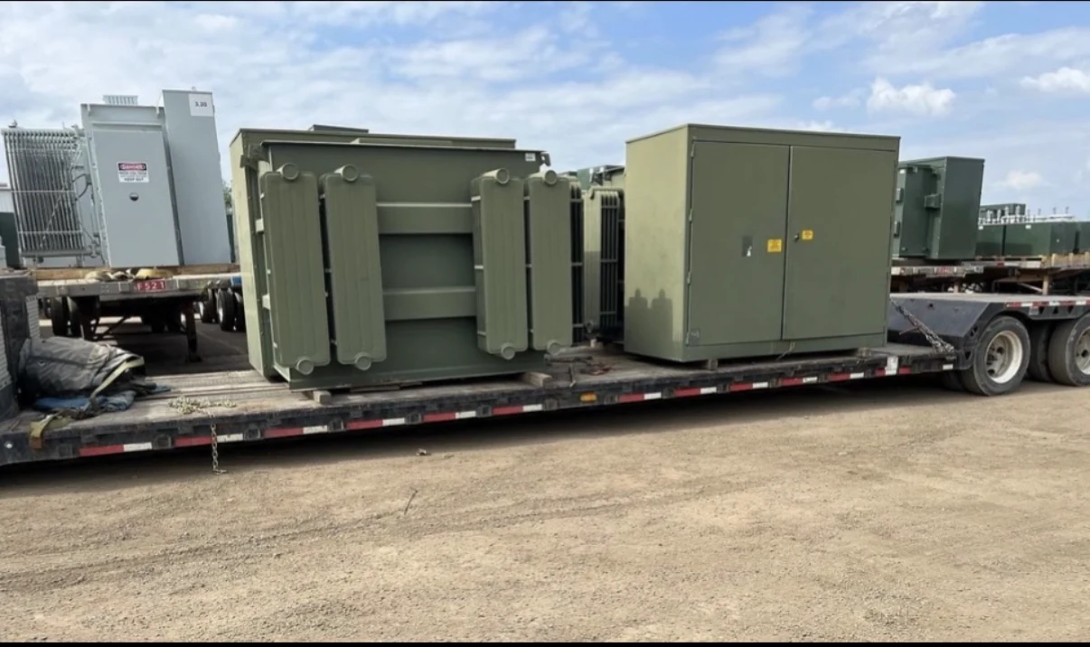Padmount transformers and enclosures loaded on a flatbed for transport.