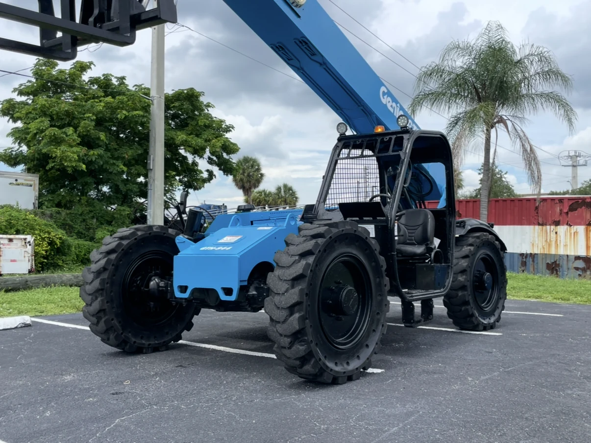 Blue telehandler parked on an asphalt equipment lot.