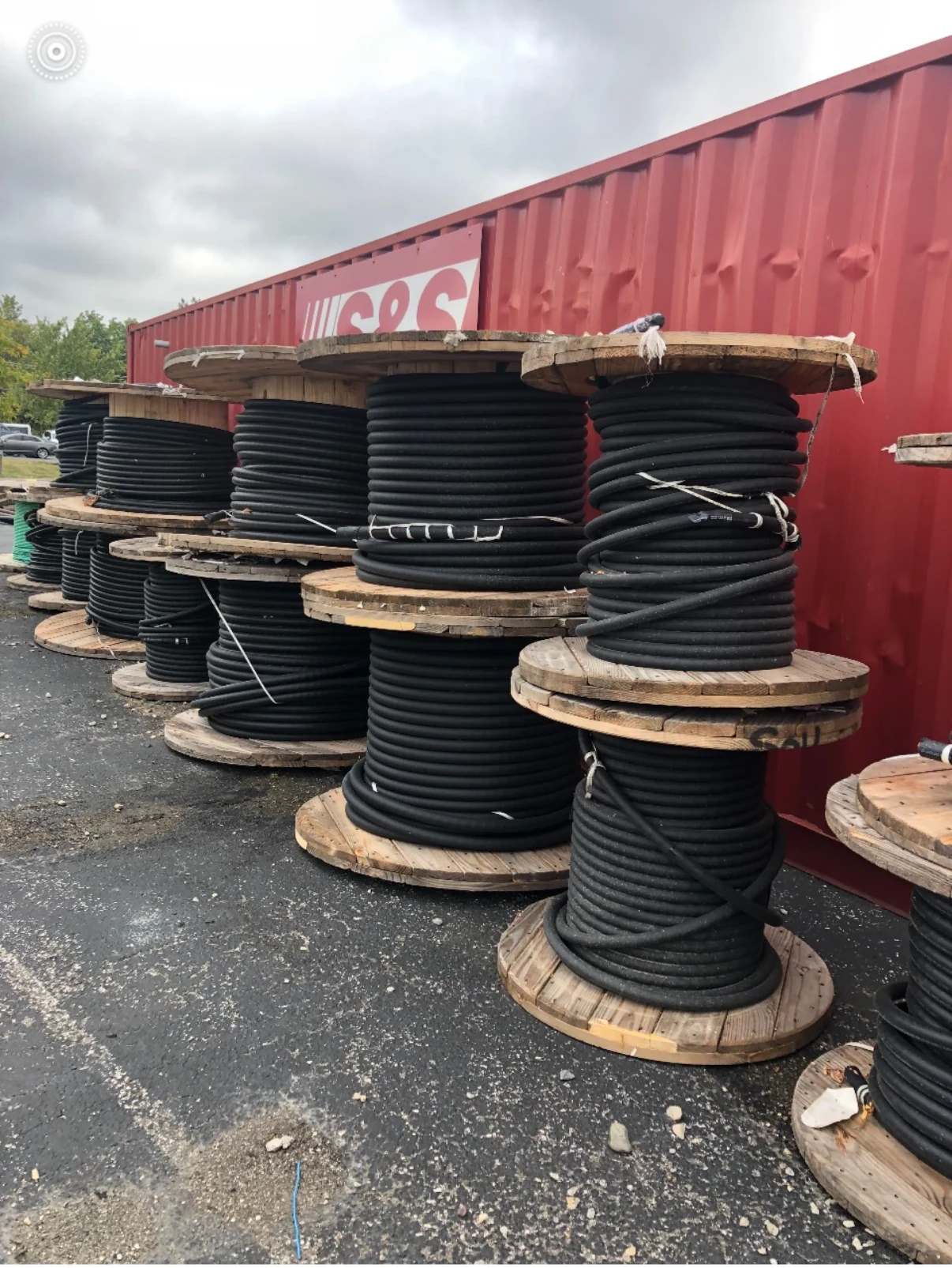 Large wooden cable spools staged beside a red shipping container.