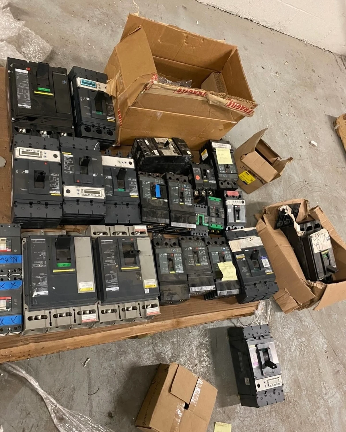 Industrial circuit breakers arranged on a pallet for inspection.