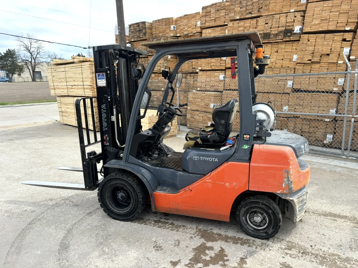 Orange and gray forklift parked near stacked materials.