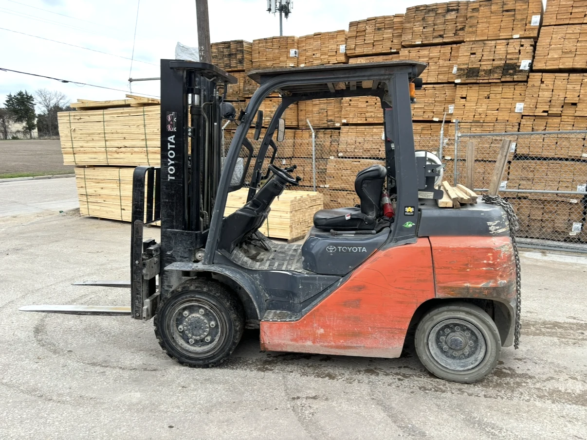 Toyota forklift parked outdoors near material stacks.