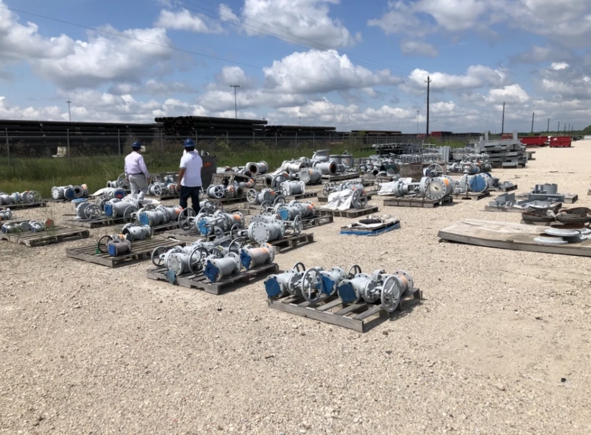 Industrial valves arranged on pallets in an outdoor recovery yard.