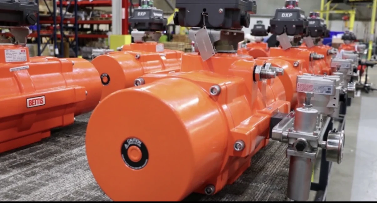 Orange industrial valve actuators on a warehouse workbench.