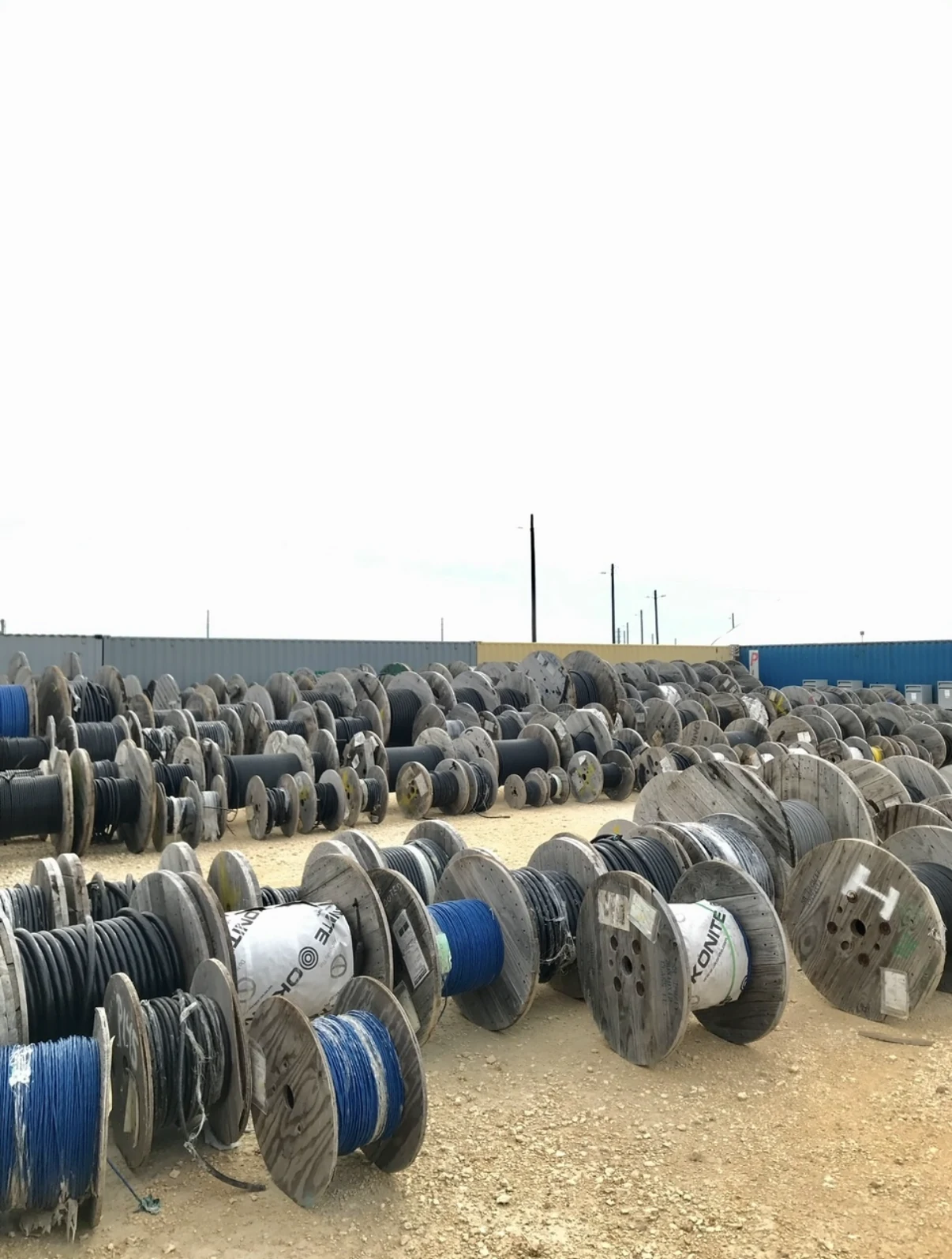 Outdoor storage yard filled with electrical cable spools.